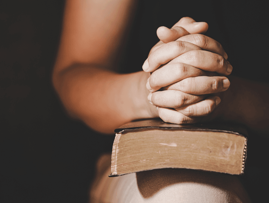 Hands folded in prayer on a Bible